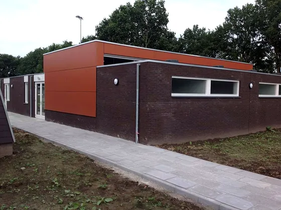 Kleedlokalen van SV Laar: gebouw van donkere baksteen met een oranje gevelpaneel
